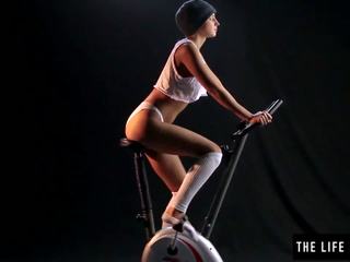 Schattig zweterig tiener bespringen een exercise bike zetel.